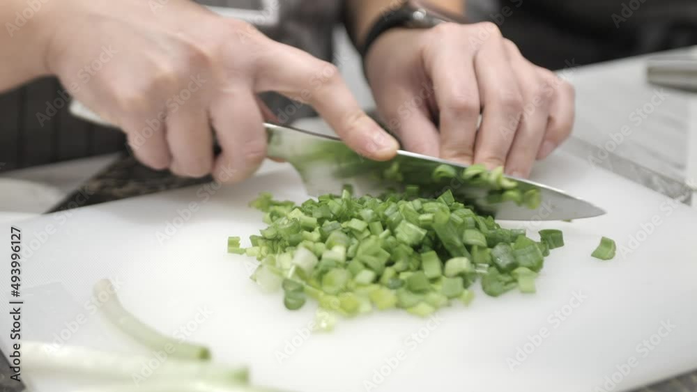 Preparation of green onion for salad. Cutting greens on the Board with a knife Preparation of green onion for salad. Cutting greens on the Board with a knife