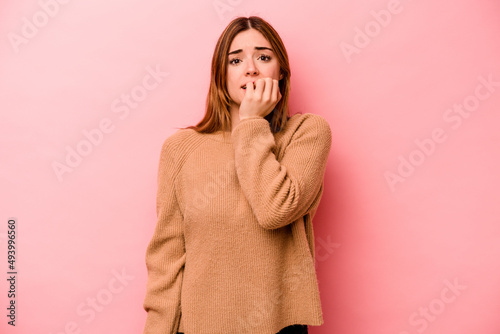 Young caucasian woman isolated on pink background biting fingernails, nervous and very anxious.