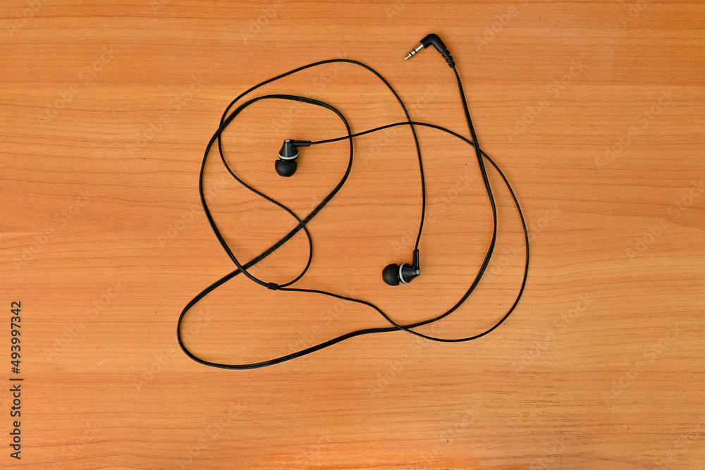 wired headphones tangled in a knot, on a wooden background wired headphones tangled in a knot, on a wooden background