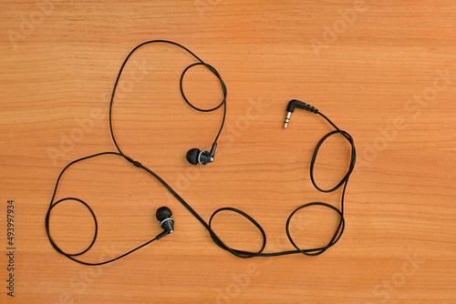 wired headphones tangled in a knot, on a wooden background