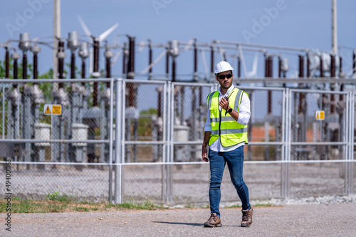 Engineer wearing uniform ,helmet  inspection electricity which production wind turbine farms rotation to generate electricity energy. Green ecological power generation wind sustainable energy concept.
