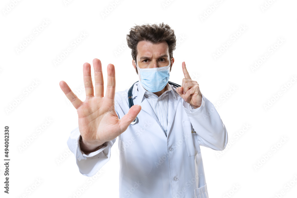 Male young doctor with stethoscope and face mask on white studio background. Looks sad, serious. Concept of healthcare and medicine, war, help, treatment Male young doctor with stethoscope and face mask on white studio background. Looks sad, serious. Concept of healthcare and medicine, war, help, treatment