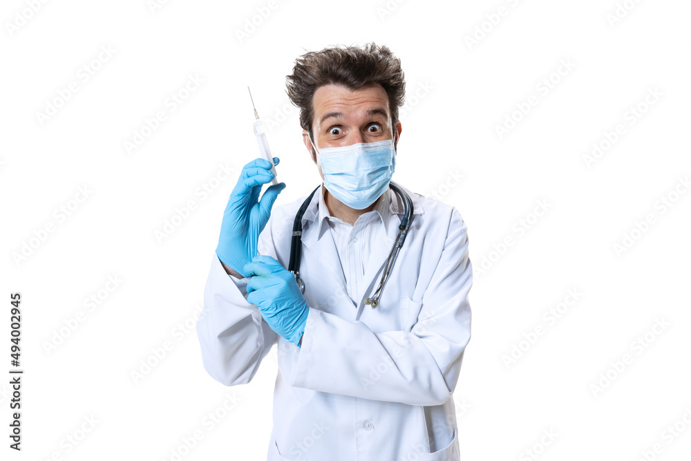 Ready for injection. Male young doctor with stethoscope and face mask on white studio background. Looks sad, serious. Concept of healthcare and medicine, war, help, treatment Ready for injection. Male young doctor with stethoscope and face mask on white studio background. Looks sad, serious. Concept of healthcare and medicine, war, help, treatment