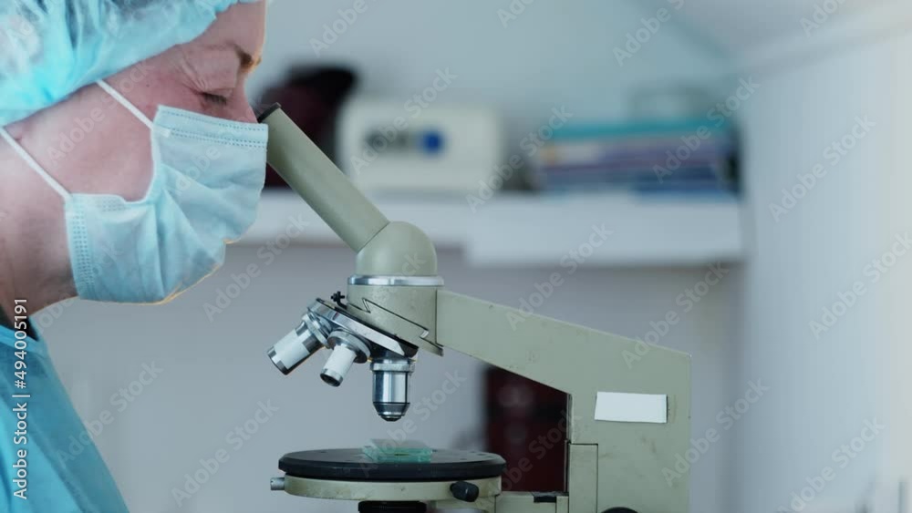 The laboratory assistant examines samples under a microscope. The assistant brings new samples. Research medicine The laboratory assistant examines samples under a microscope. The assistant brings new samples. Research medicine
