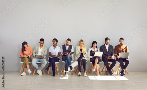 Modern way to communicate. Woman in row with people who came for interview and are busy reading resumes or surfing internet. Concept of human resources, employment, customers and electronic devices. photo