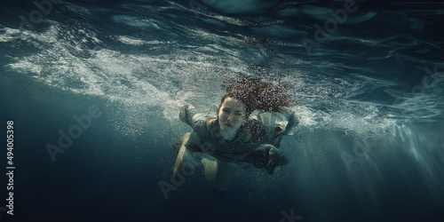 A woman in a dress swims under water as she flies in weightlessness Fototapet