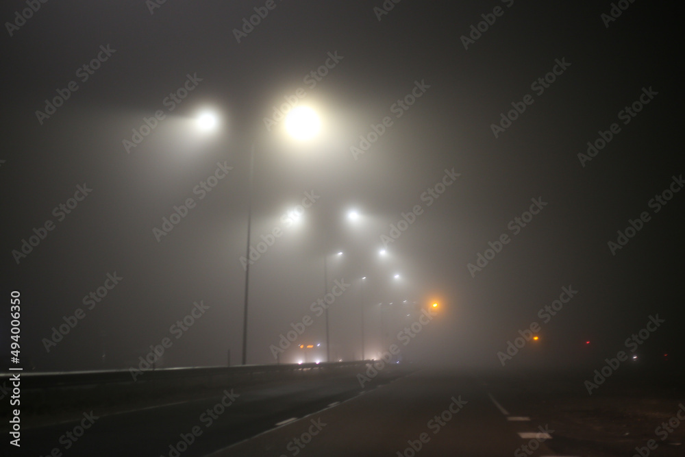 Misty city view of highway with traffic and car lights.