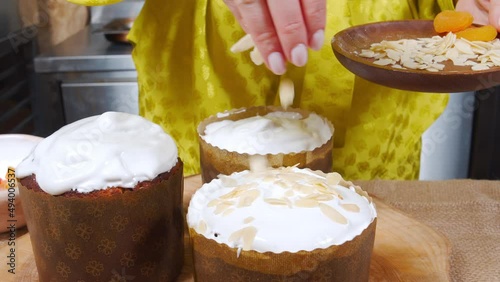 Close-up of cooking Easter cake. Female hands decorating delicious Easter cakes with almonds and candied fruits.
