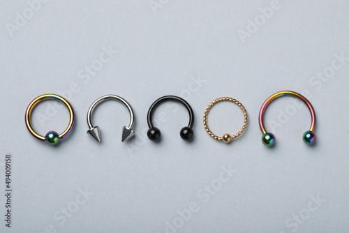 Foto Stylish captive bead and horseshoe rings on light grey background, flat lay