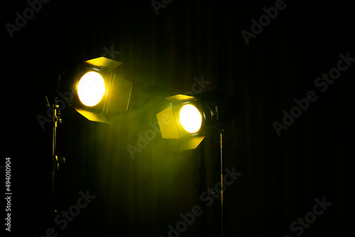Bright yellow spotlights on dark stage, space for text