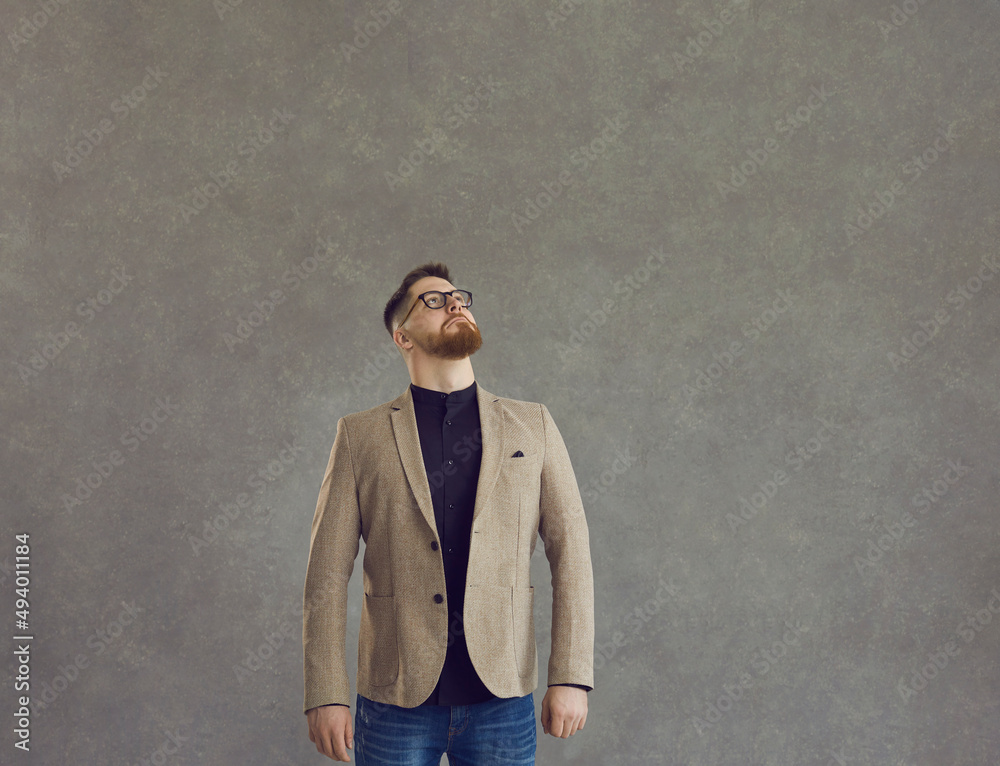 Serious smart caucasian business man looking up studio shot over grey background. Thoughtful office worker, male entrepreneur standing with pensive expression. Planning and contemplation Serious smart caucasian business man looking up studio shot over grey background. Thoughtful office worker, male entrepreneur standing with pensive expression. Planning and contemplation