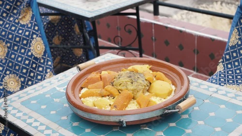 A person lifting the conical lid of a traditional moroccan tajini of couscous with vegetables in Fes, Morocco.
