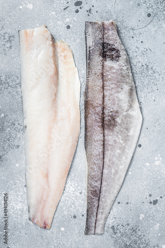 Two raw haddock fish fillets on kitchen table. Gray background. Top view photo