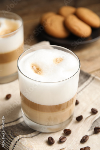 Delicious latte macchiato and coffee beans on wooden table