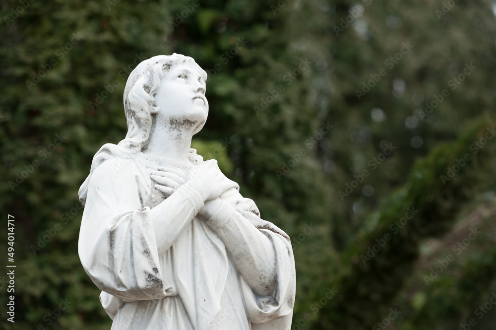 Sculpture of a grieving woman looking up with arms folded on her chest Sculpture of a grieving woman looking up with arms folded on her chest