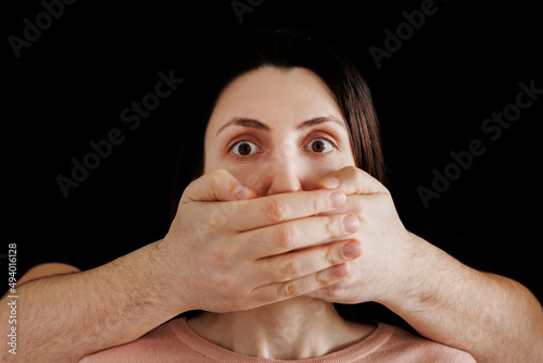 Man hand closes woman mouth, russian flag in the background. censorship concept, no personal opinion, closeup. woman resists the censorship photo