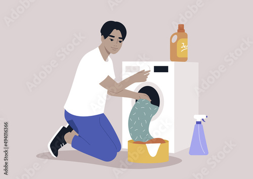 A young male Asian character loading a washing machine with a pile of laundry, domestic chores