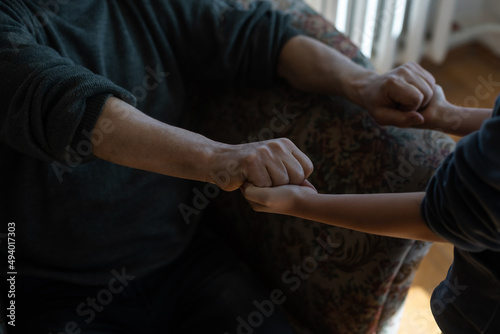 the hands of the child embracing a hand of the old man © Angelov