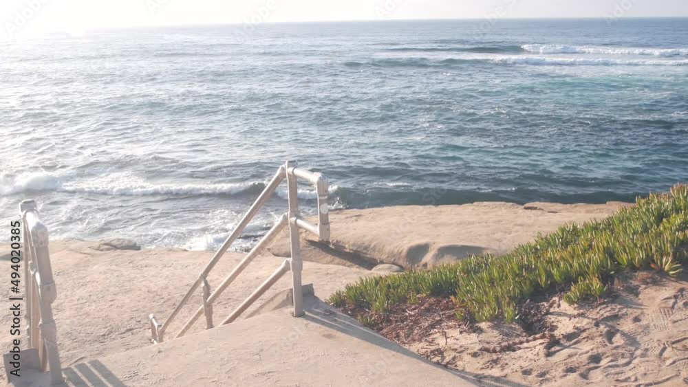 Beach access, stairs to ocean shore, La Jolla cove, California coast landscape, USA. Sea waves, cliff and green succulent ice plant. Water surface seascape, summer vacations, tourist waterfront resort Beach access, stairs to ocean shore, La Jolla cove, California coast landscape, USA. Sea waves, cliff and green succulent ice plant. Water surface seascape, summer vacations, tourist waterfront resort