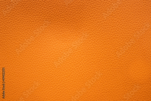 Orange faux leather background is used to wrap book covers or to repair everyday leather sofa seats and appliances. background and pattern on the Orange faux leather have space for text.
