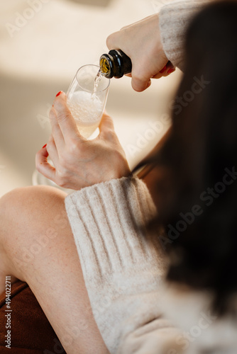 a woman pours champagne into a glass. sparkling wine for a party or hen party. the tradition of toasting and drinking alcohol on holidays.