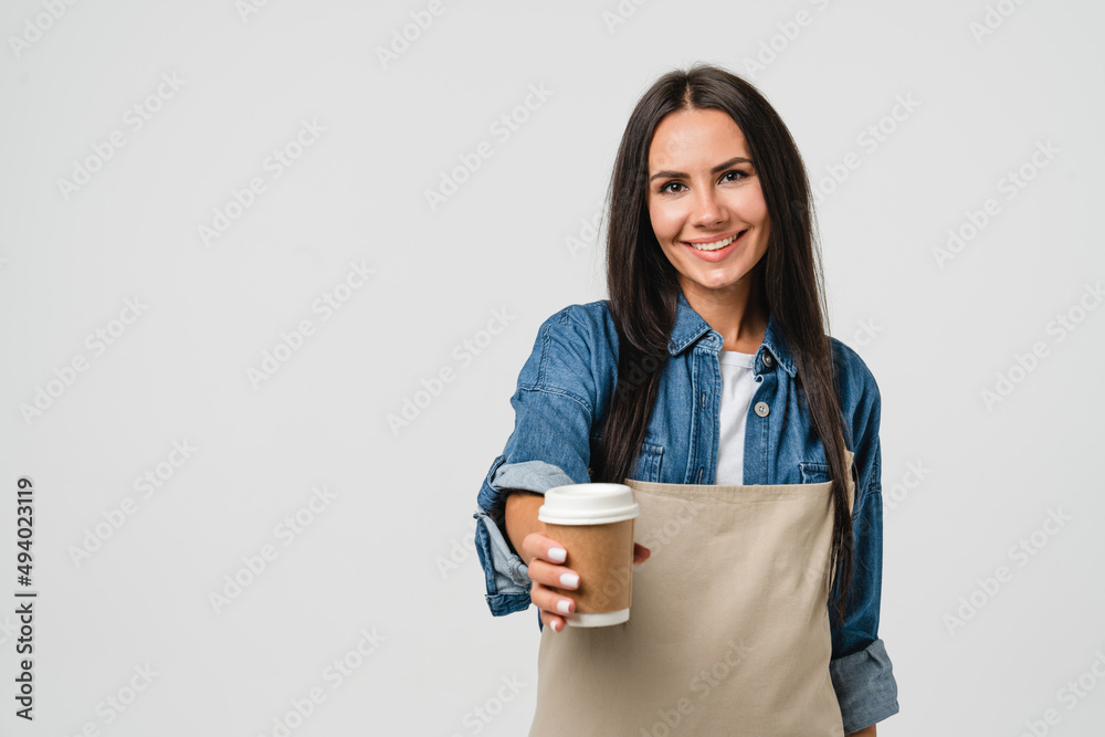 Friendly smiling caucasian young female woman barista bar tender coffee maker in apron giving holding coffee tea hot beverage cup with decaf sugar-free isolated in white Friendly smiling caucasian young female woman barista bar tender coffee maker in apron giving holding coffee tea hot beverage cup with decaf sugar-free isolated in white