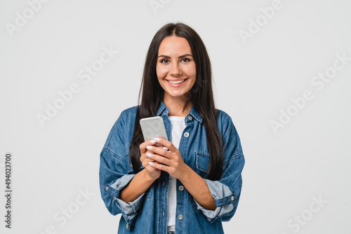 Smiling caucasian young woman girl using smart phone cellphone for e-learning, e-commerce, e-banking online, mobile applications, making bet in casino isolated in white background