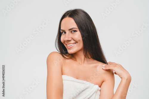 Body skin face hair care. Young caucasian healthy woman in spa bath towel looking at camera, applying beauty treatment for rejuvenation and hydration isolated in grey background