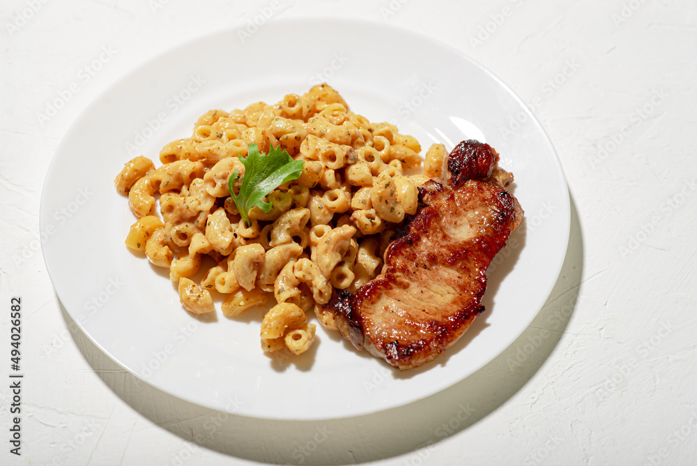 Figured Italian pasta in sauce. Pieces of chopped fried meat. Minimalistic food design. White background. Figured Italian pasta in sauce. Pieces of chopped fried meat. Minimalistic food design. White background.