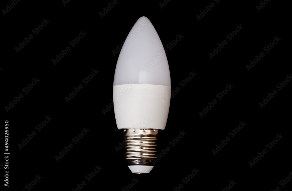 A small pointed modern LED lamp with a metal base with a plastic housing isolated on a black background A small pointed modern LED lamp with a metal base with a plastic housing isolated on a black background