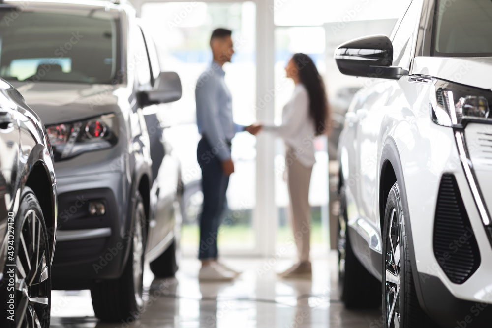 Unrecognizable man and woman shaking hands at auto showroom Unrecognizable man and woman shaking hands at auto showroom
