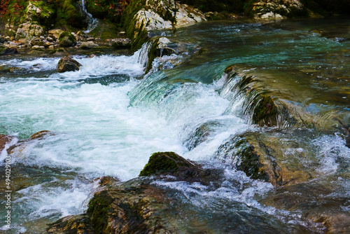 small waterfall on a river with blue clean water in a wild forest