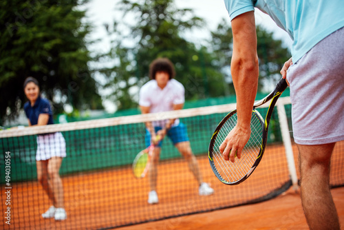 Tennis sport people concept. Mixed doubles player hitting tennis ball with partner standing near net photo