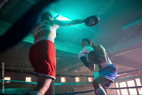 Boxer girls making progress during training boxing. Low angle view of two young girls competing with each other, practicing punches and reaction in gym to win match.Sport and healthy lifestyle concept