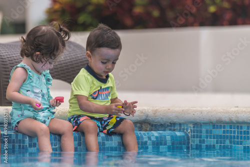 Two young babies playing at the pool on a warm summer day