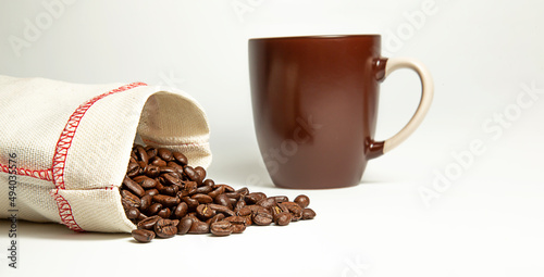 Coffee beans spilled out of the bag on a white background.
