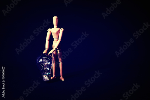 wooden mannequin is posing with lightbulb, creative thinking concept