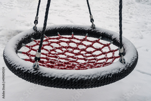 Empty children rope swing with snow in winter time at playground
