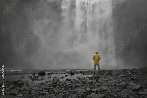 Man with yellow raincoat close to Skogafoss waterfall in Iceland photo