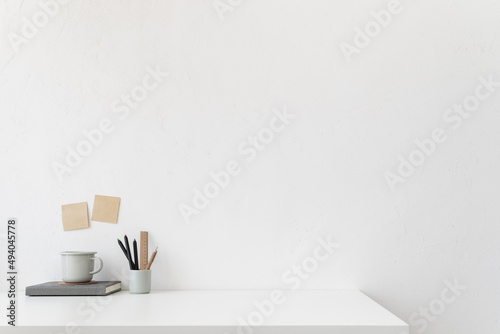 Office table, empty desk with supplies and white wall copy space. 