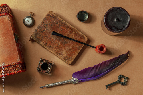 Private detective investigation game play objects. A vintage pipe, a quill pen, a retro ink well and other mysterious objects, overhead flat lay shot