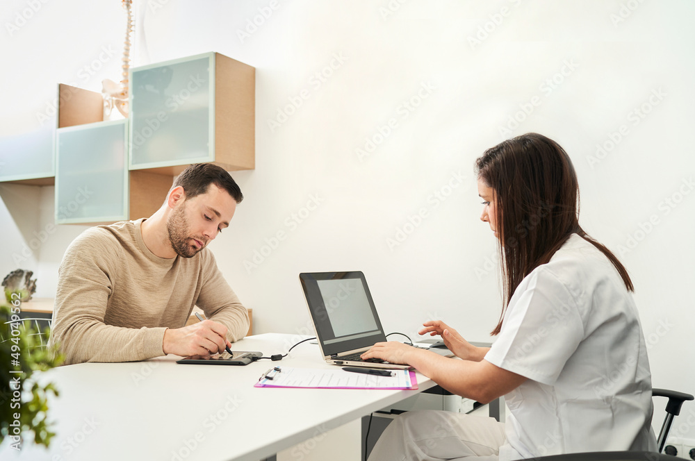 The physical therapist and the patient fill out a patient form. The physical therapist and the patient fill out a patient form.