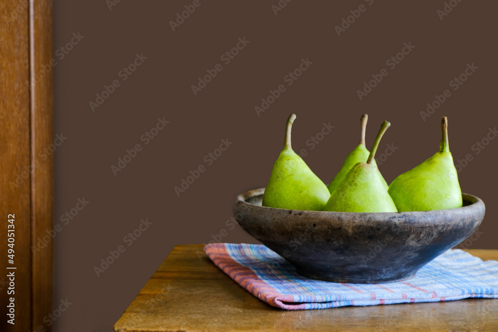 Green pears in a clay ancient old plate on a wooden table. Dark brown food template. Empty space. Food, ingredient, fall color, vitamin, fresh fruits, vegan organic produce, healthy nutrition, harvest Green pears in a clay ancient old plate on a wooden table. Dark brown food template. Empty space. Food, ingredient, fall color, vitamin, fresh fruits, vegan organic produce, healthy nutrition, harvest