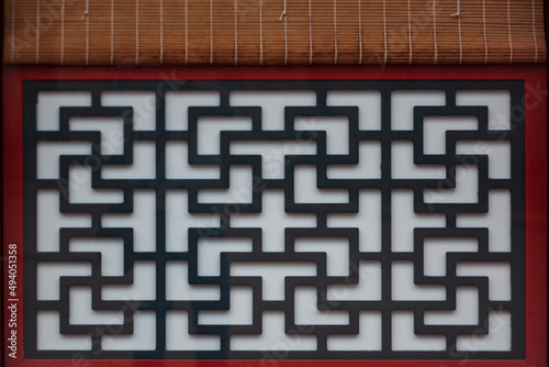 Chinese deigns in a window with wood shades.