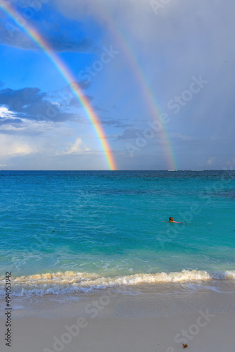 double rainbow over the sea with swimmer