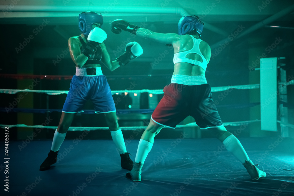 Female boxers practicing active boxing on ring. Two young girls performing intense bout