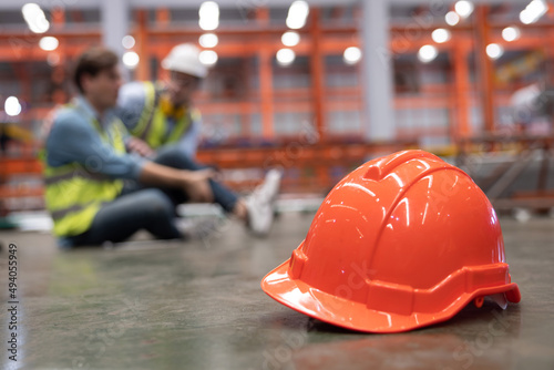 Red Hard Hat with Blurred Injured Factory Workers as Background