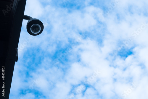 Protected surveillance camera on the background of the sky with clouds. Weatherproof CCTV Camera
