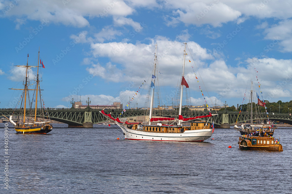 several old sailing ships parked on the Neva River in St. Petersburg against the blue sky and city