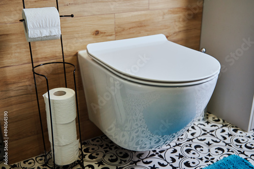 Ceramic toilet bowl and toilet paper in bathroom interior photo